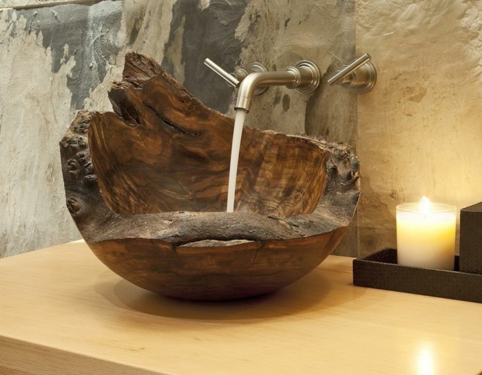 freistehender Holzbecken mit unregelmäßiger Form, Kupferhahn mit Wandmontage, Tisch aus hellem Holz, Wand mit Steinoptik